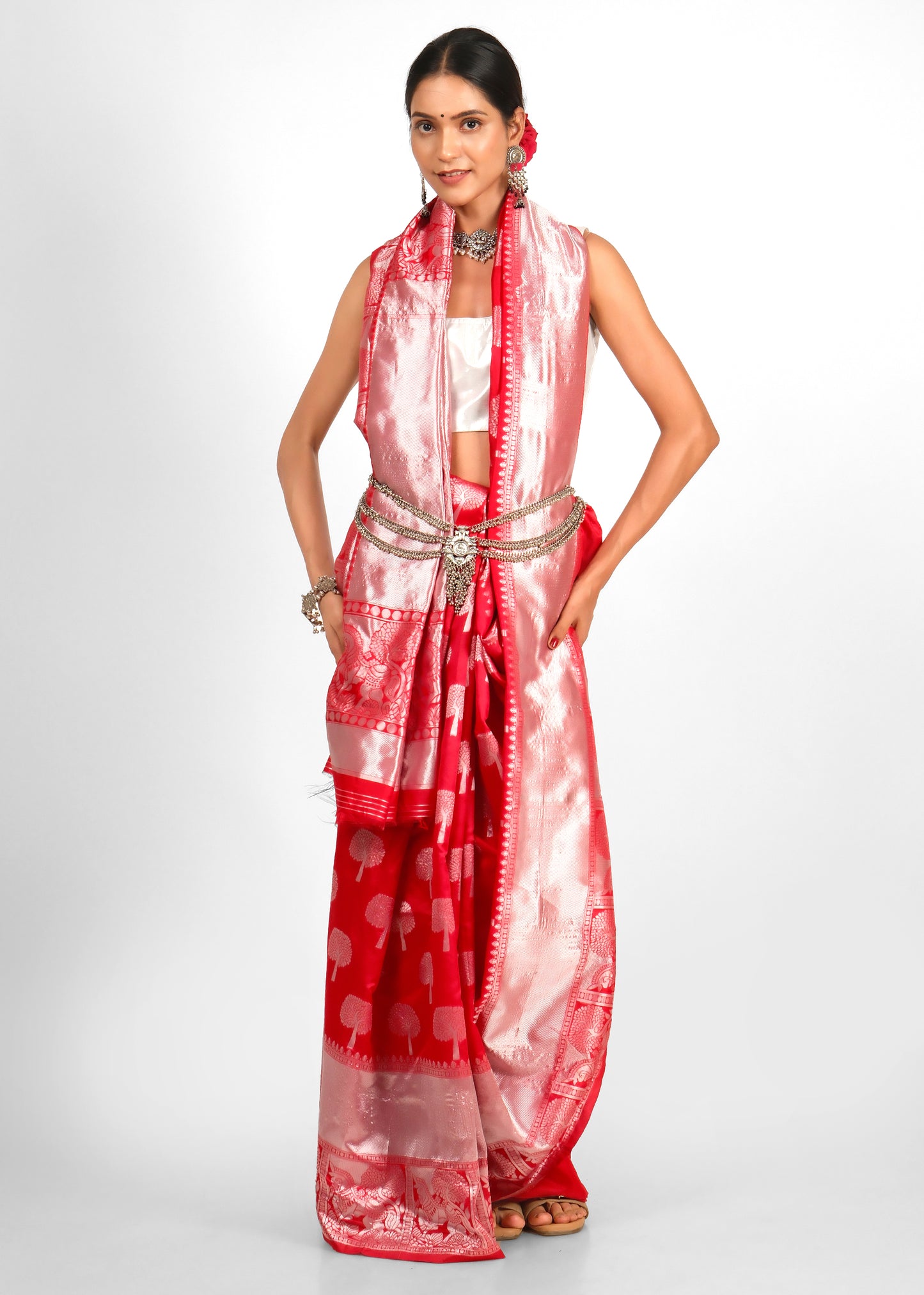 Model in a stunning red and silver saree with intricate tree motifs and a bold silver belt, showcasing traditional Indian bridal fashion.