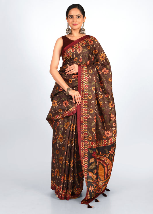 Woman wearing a deep brown floral saree with contrasting red border, styled with traditional silver jewelry for a cultural occasion.