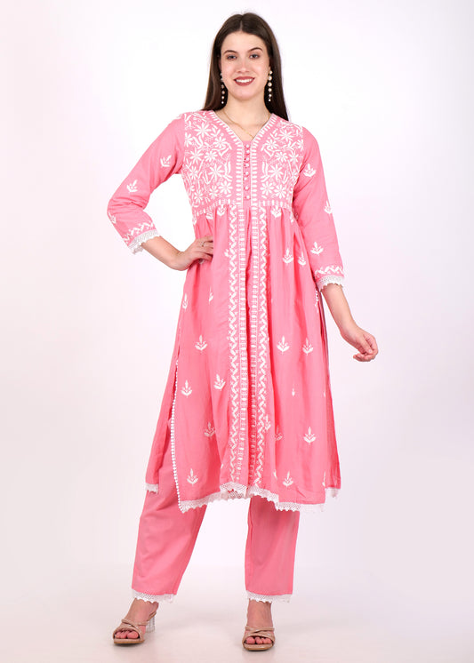 Woman wearing a pink embroidered Anarkali kurta with white floral detailing and lace borders, styled with matching pants.