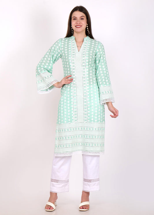 Woman wearing a pastel pink embroidered kurta with white lace detailing and matching white pants, styled with pearl earrings and open hair