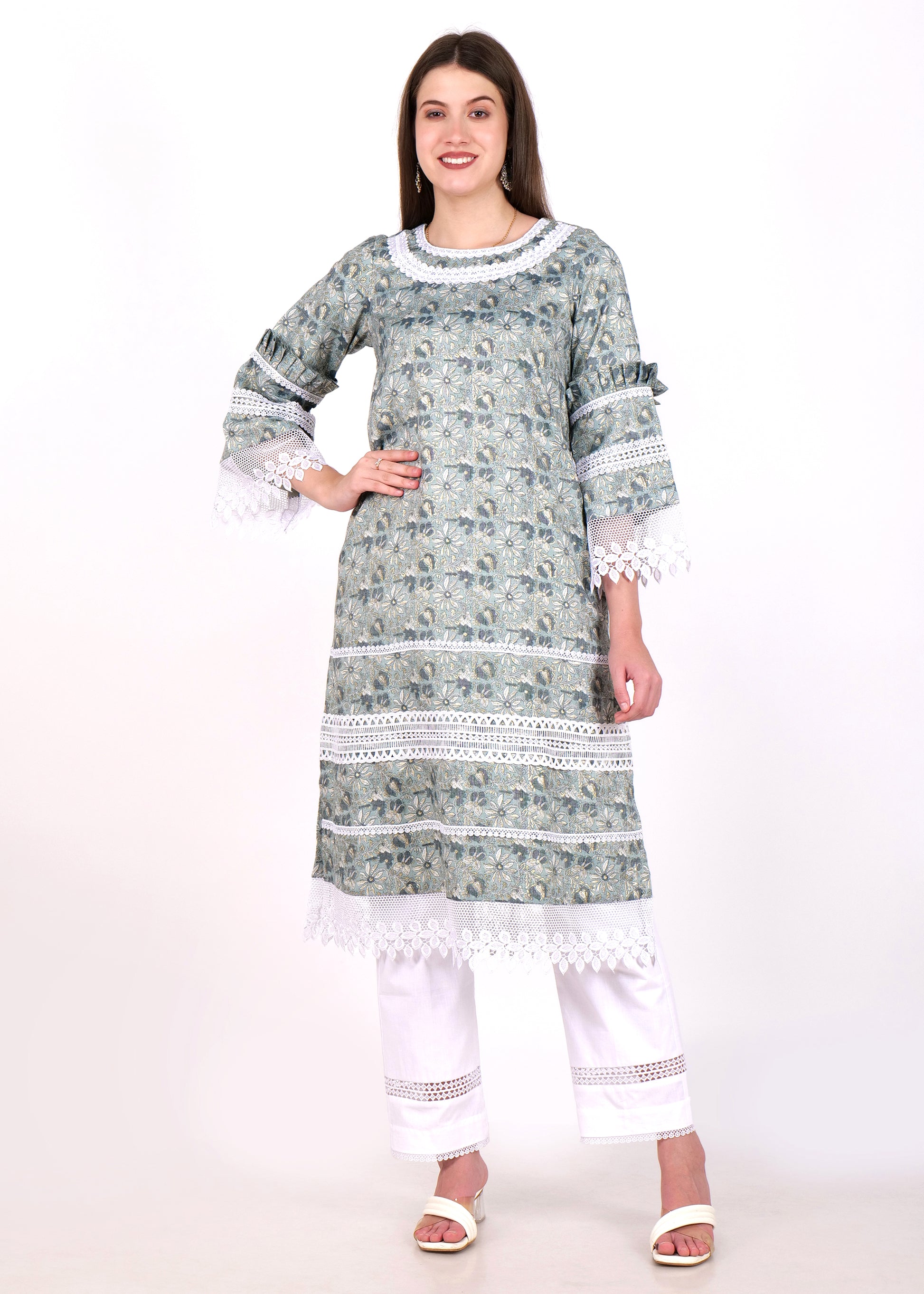 Woman wearing a traditional green printed kurta with lace detailing, paired with white pants and heels, standing confidently