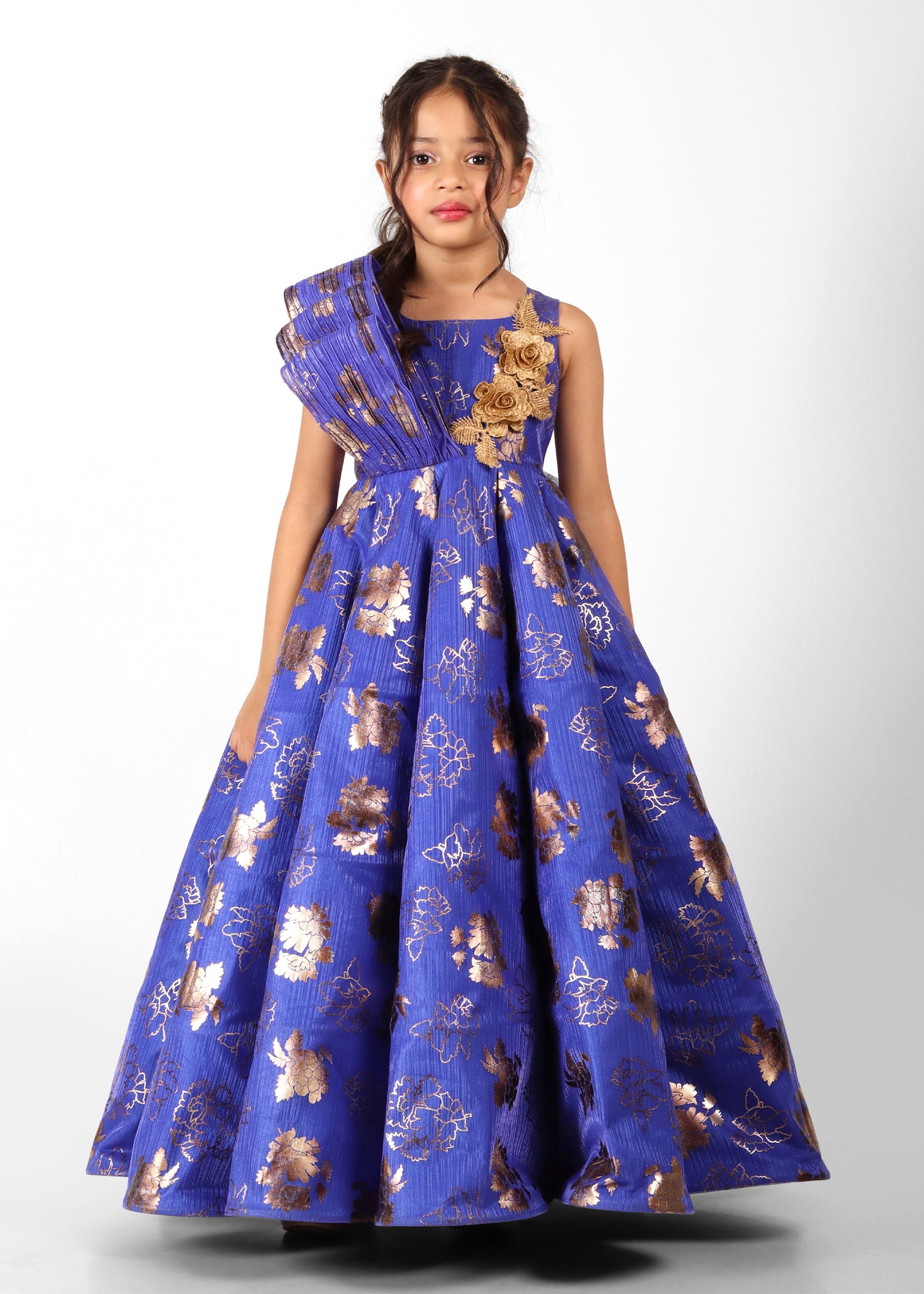 Girl wearing a blue and gold floral gown with elegant design details, standing with hand on hip