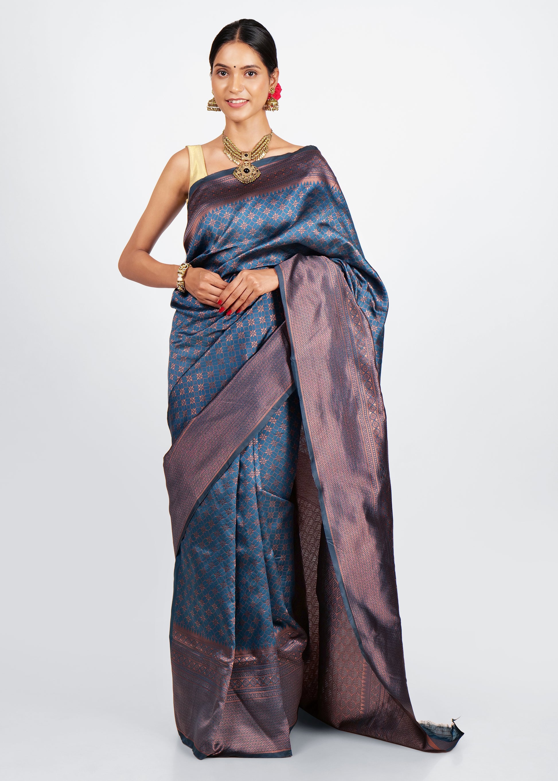 Woman in elegant navy blue and copper Kanjivaram silk saree with intricate floral motifs, styled with traditional gold jewelry