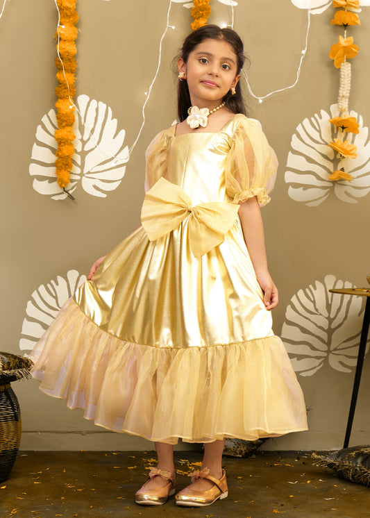  A young girl in a shimmering golden gown with puffed sleeves, a large bow at the waist, and delicate accessories, standing in a festive setting decorated with marigold flowers.