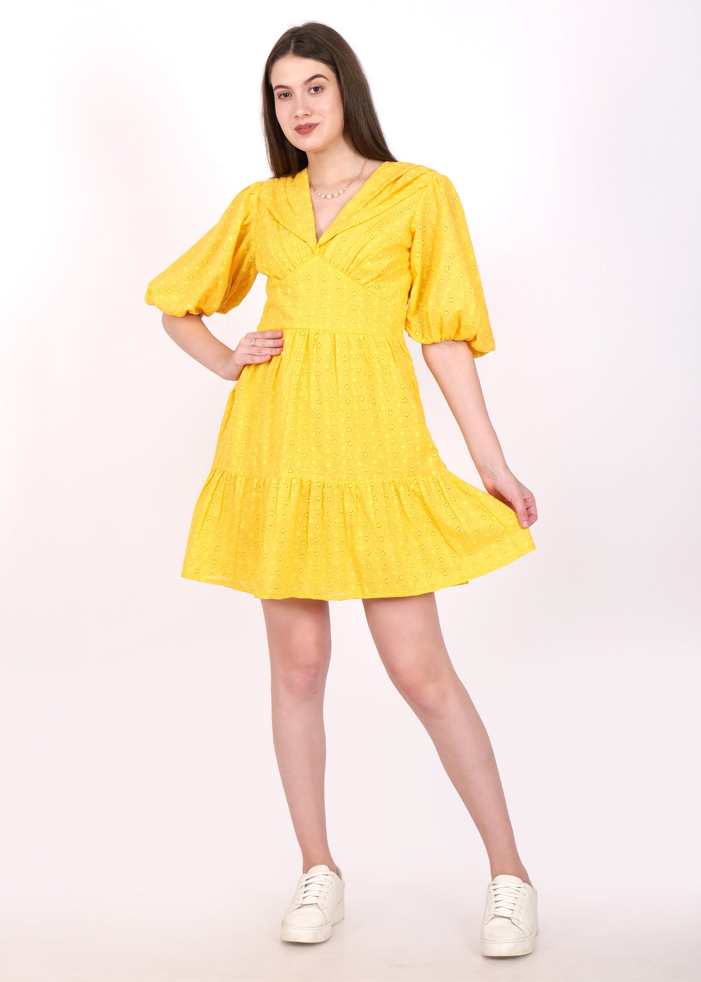 Woman wearing a vibrant yellow dress with puff sleeves and a V-neck, showcasing a casual, summer look with white sneakers