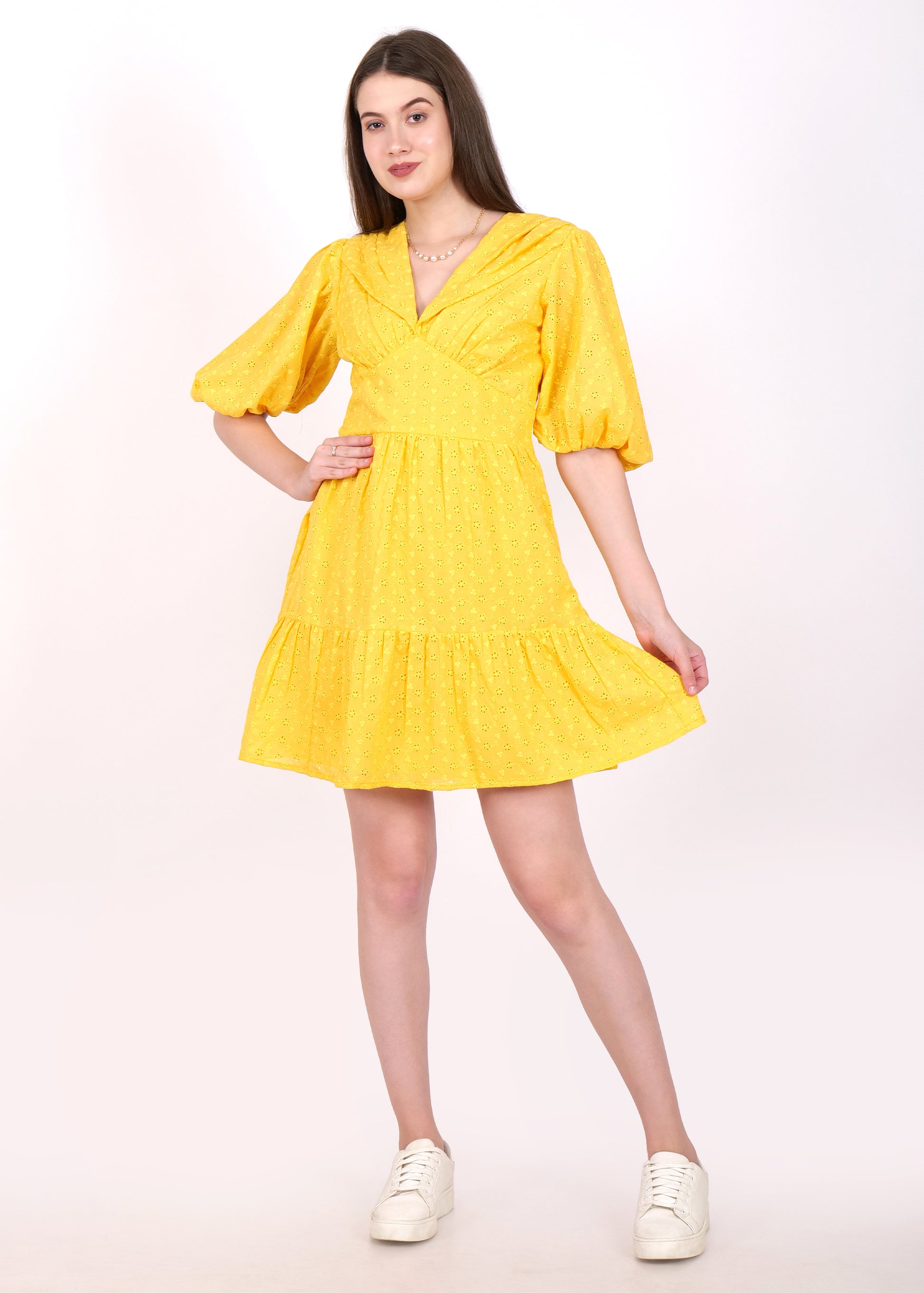 Woman wearing a vibrant yellow dress with puff sleeves and a V-neck, showcasing a casual, summer look with white sneakers