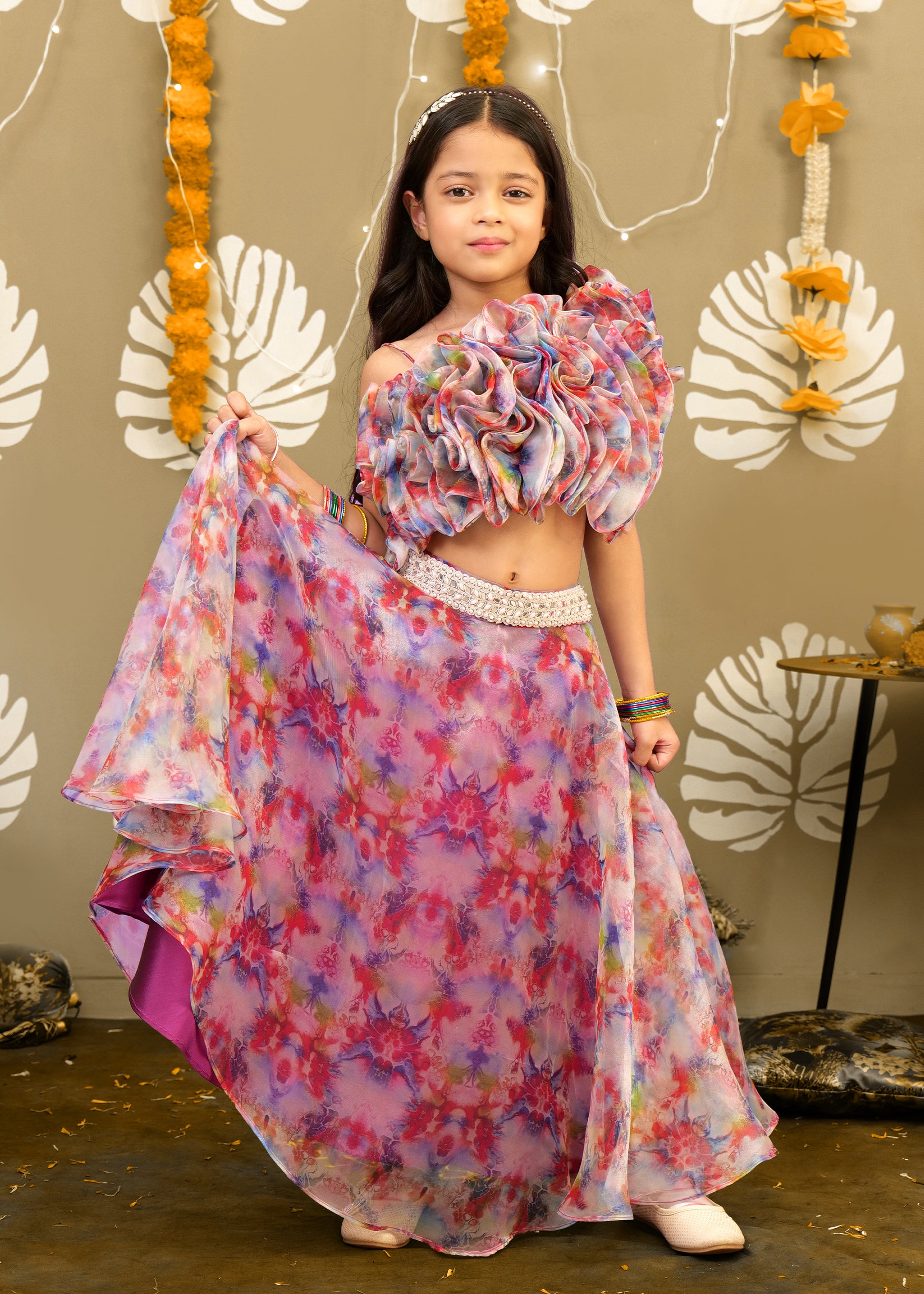 Young girl dressed in a colorful lehenga with floral designs, showing the full flowing skirt, posing with confidence.