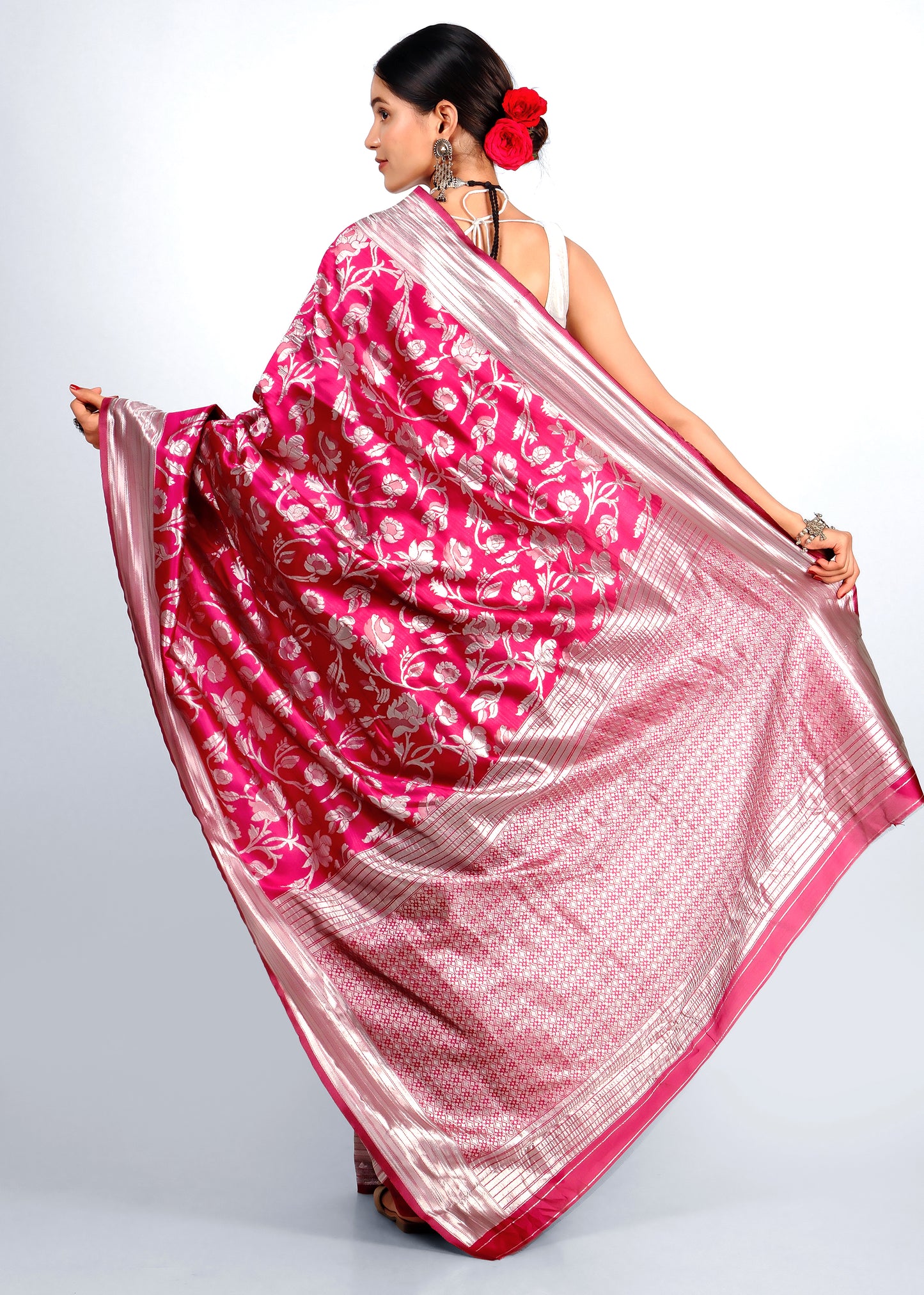 Rear view of a model showcasing the luxurious pink and silver Banarasi silk saree's detailed floral patterns and opulent pallu draped gracefully.