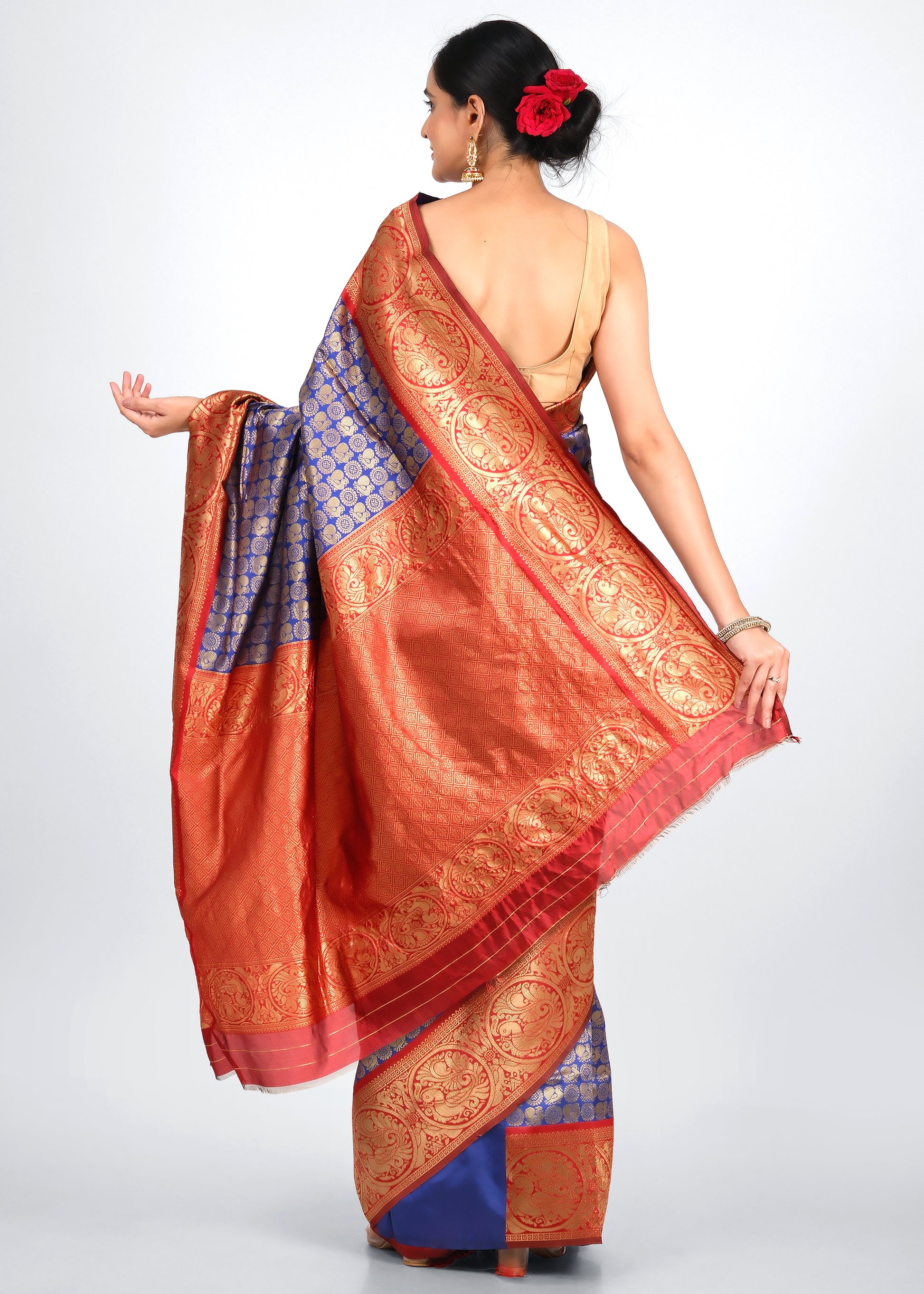 Back view of a woman showcasing the red pallu of a Banarasi silk saree with gold woven patterns, exuding luxury and elegance