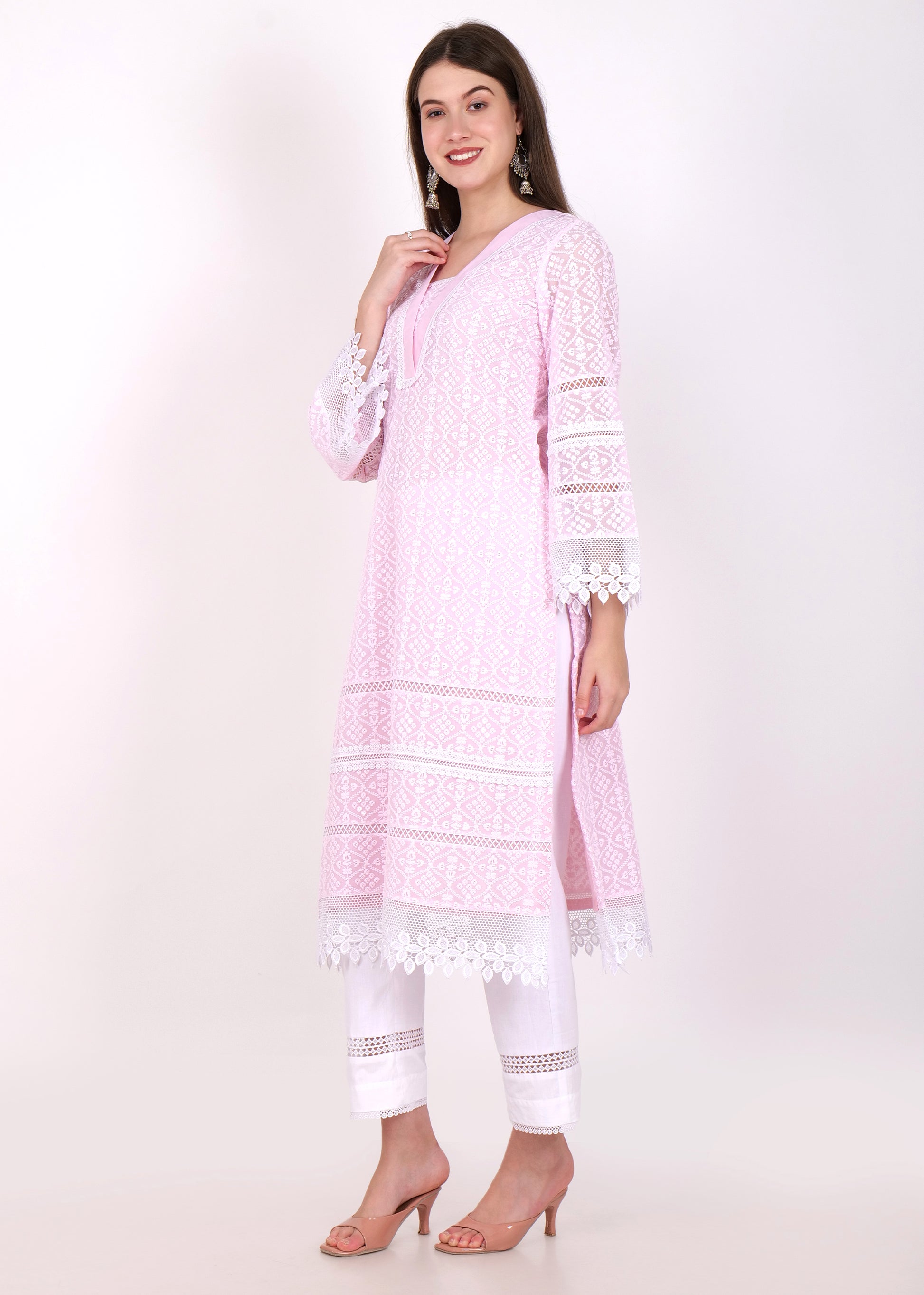 Side view of a woman wearing a pastel pink kurta with elegant lace sleeves, paired with white trousers