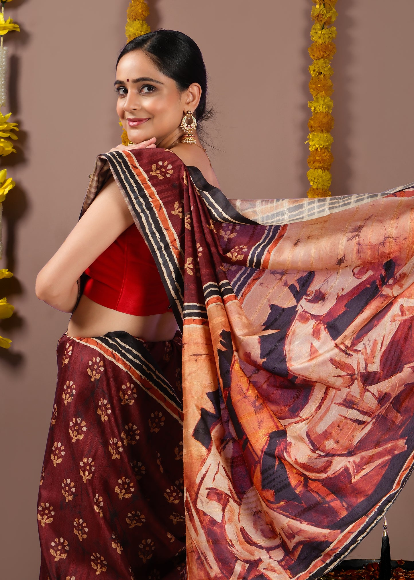 Side view of a woman showcasing the intricate Kalamkari pallu of a maroon art silk saree.