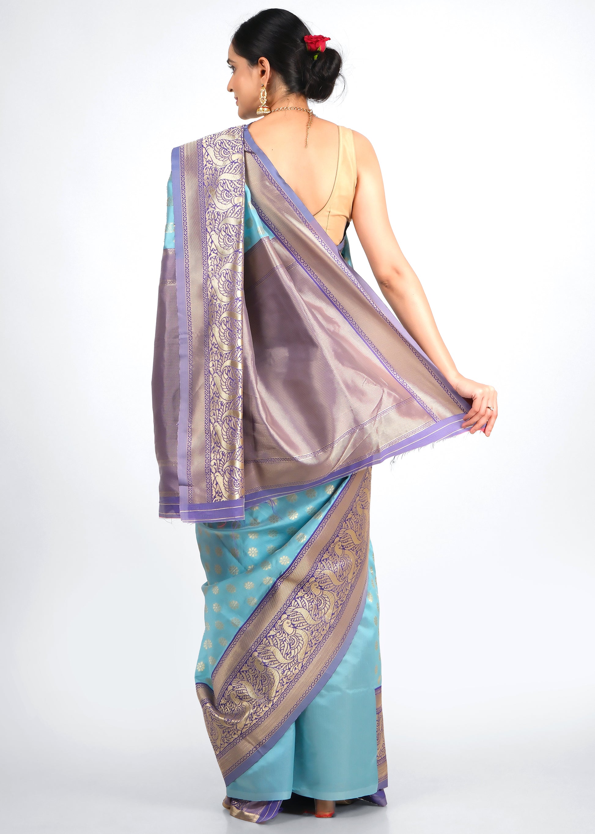 Back view of a model in a turquoise blue silk saree with a rich purple pallu featuring gold zari designs, emphasizing traditional craftsmanship.