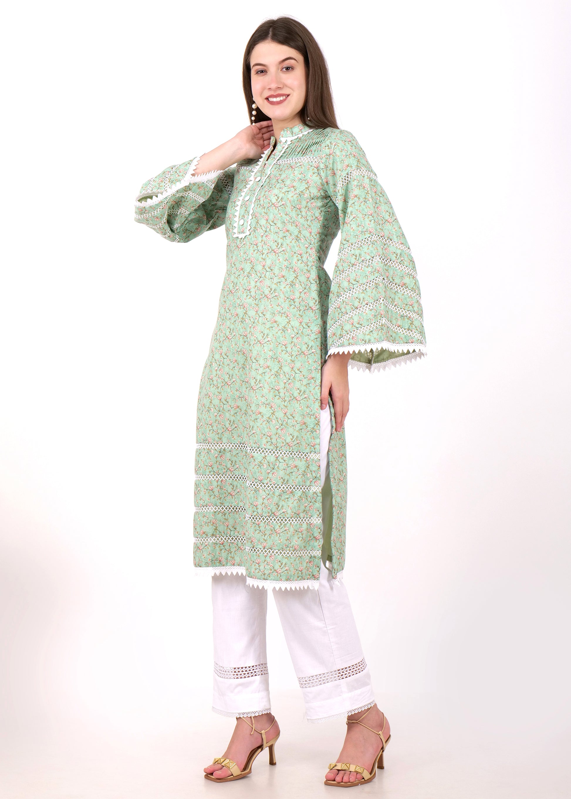 Stylish woman in a green floral kurta and white pants, showcasing the delicate lacework and flared sleeves, striking a side pose