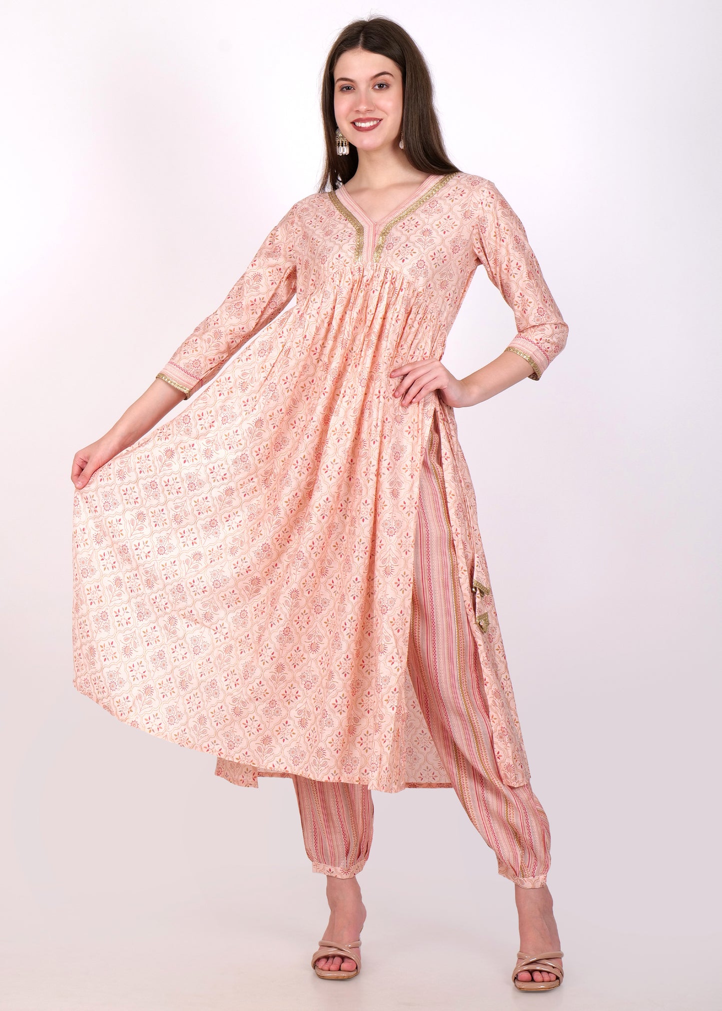 "Flowy peach Anarkali dress with delicate floral prints and matching striped salwar, ideal for festive occasions."
