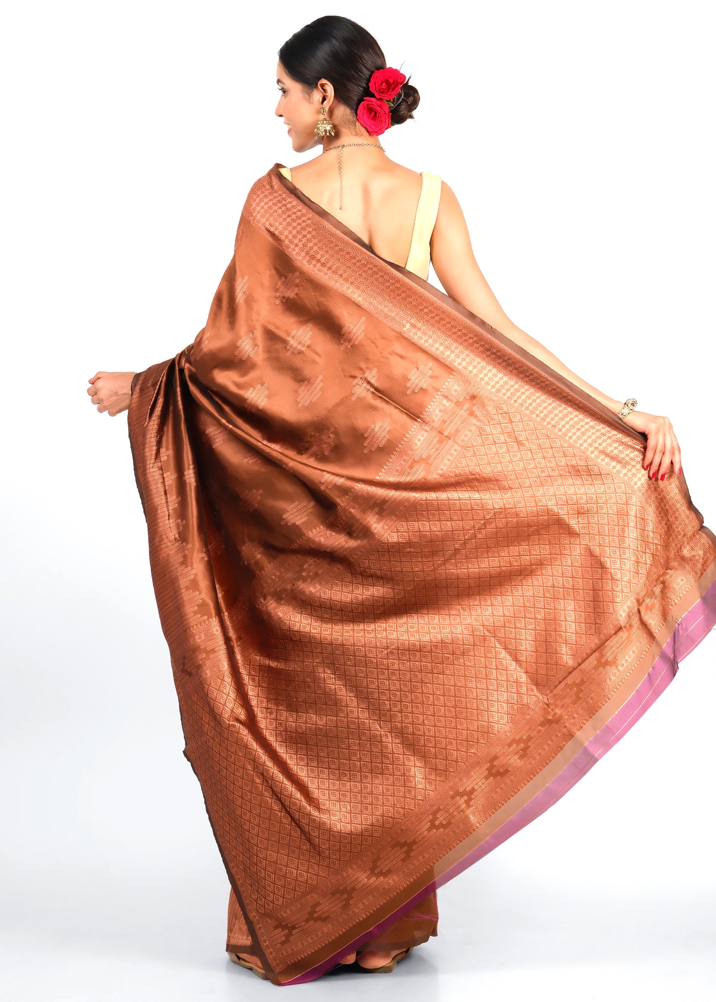 Back view of a model wearing a rich brown silk saree with a detailed pallu, adorned with traditional motifs and accessories