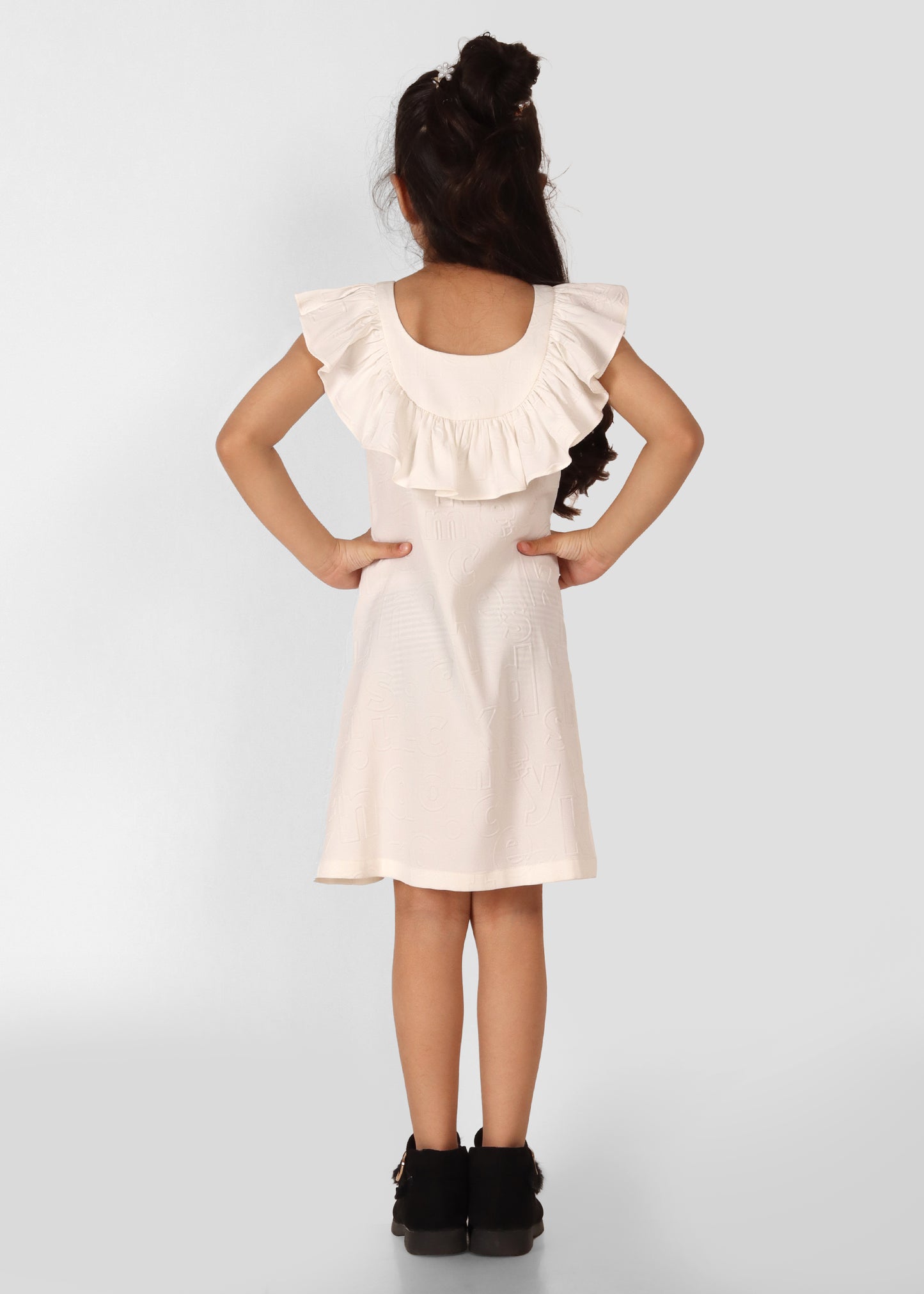 Back view of a girl in a cream ruffle-sleeve dress, showcasing detailed back design and black fur-trimmed ankle boots