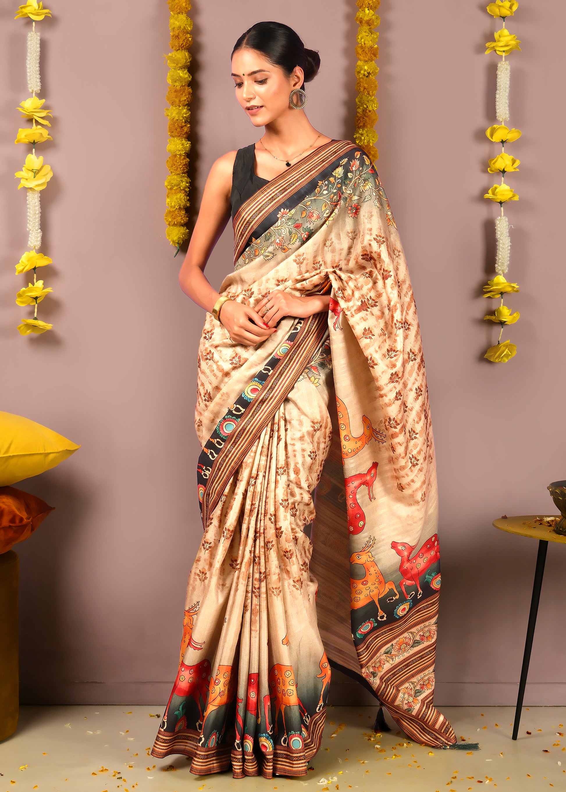 Model gracefully draping a beige saree with multicolored animal motifs and floral accents, perfect for traditional Indian celebrations.