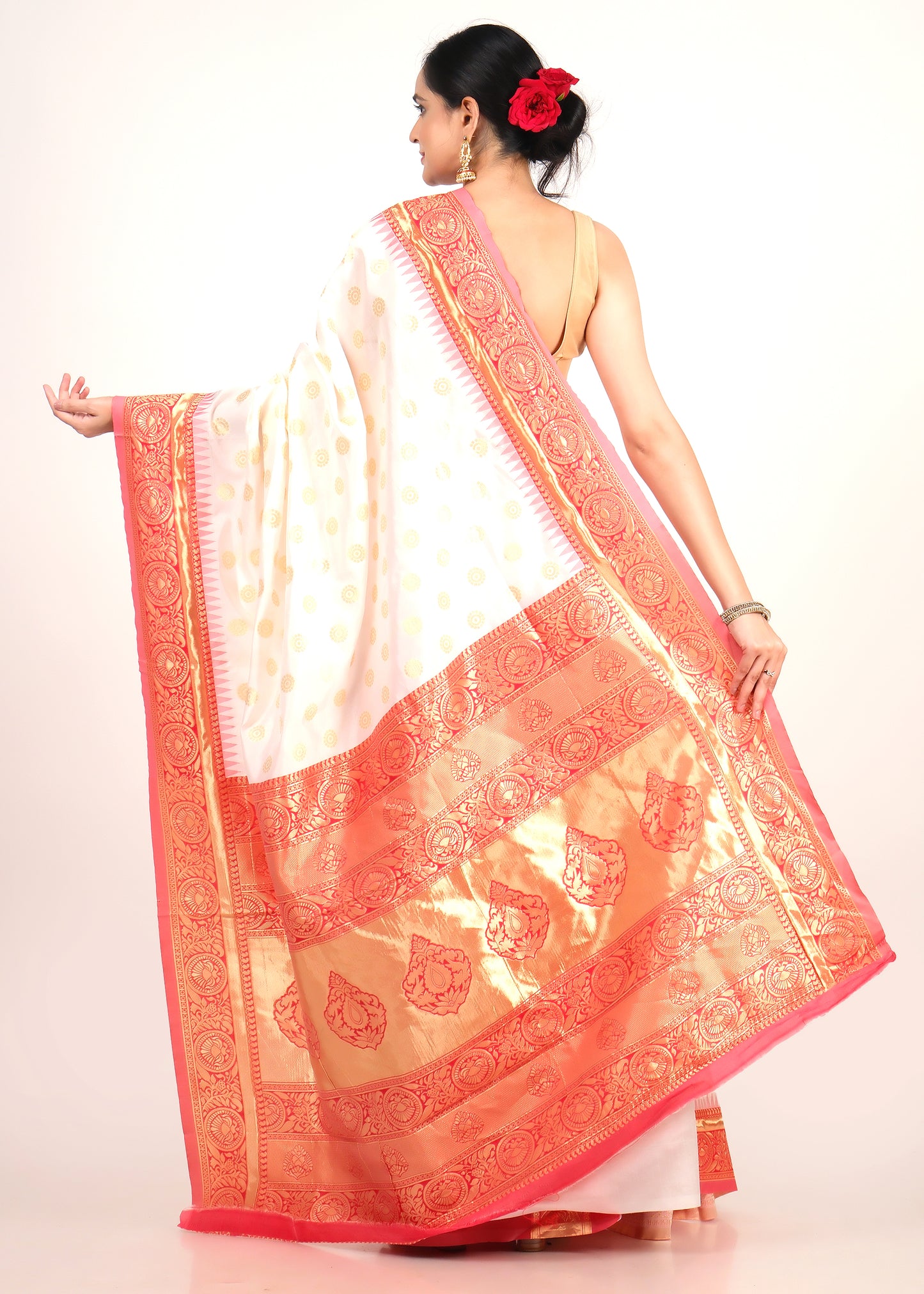 Back view of a model showcasing the rich pallu of the white and orange silk saree with ornate golden patterns