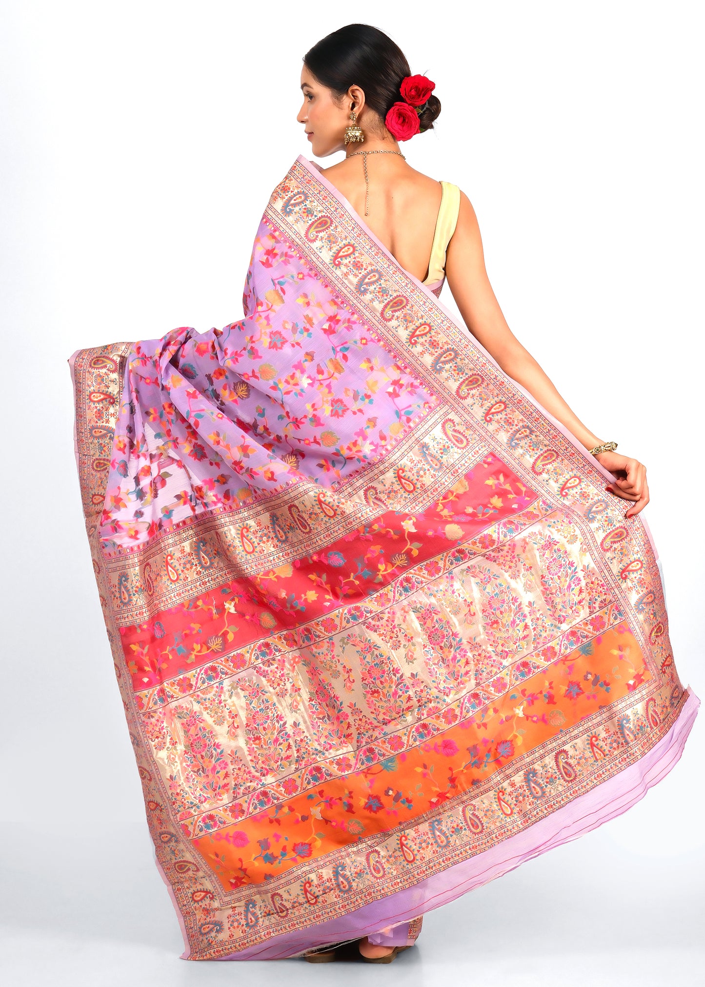 Back view of a woman in a lavender saree with a bold red and gold pallu, accented by intricate floral and paisley patterns, highlighting the rich traditional design