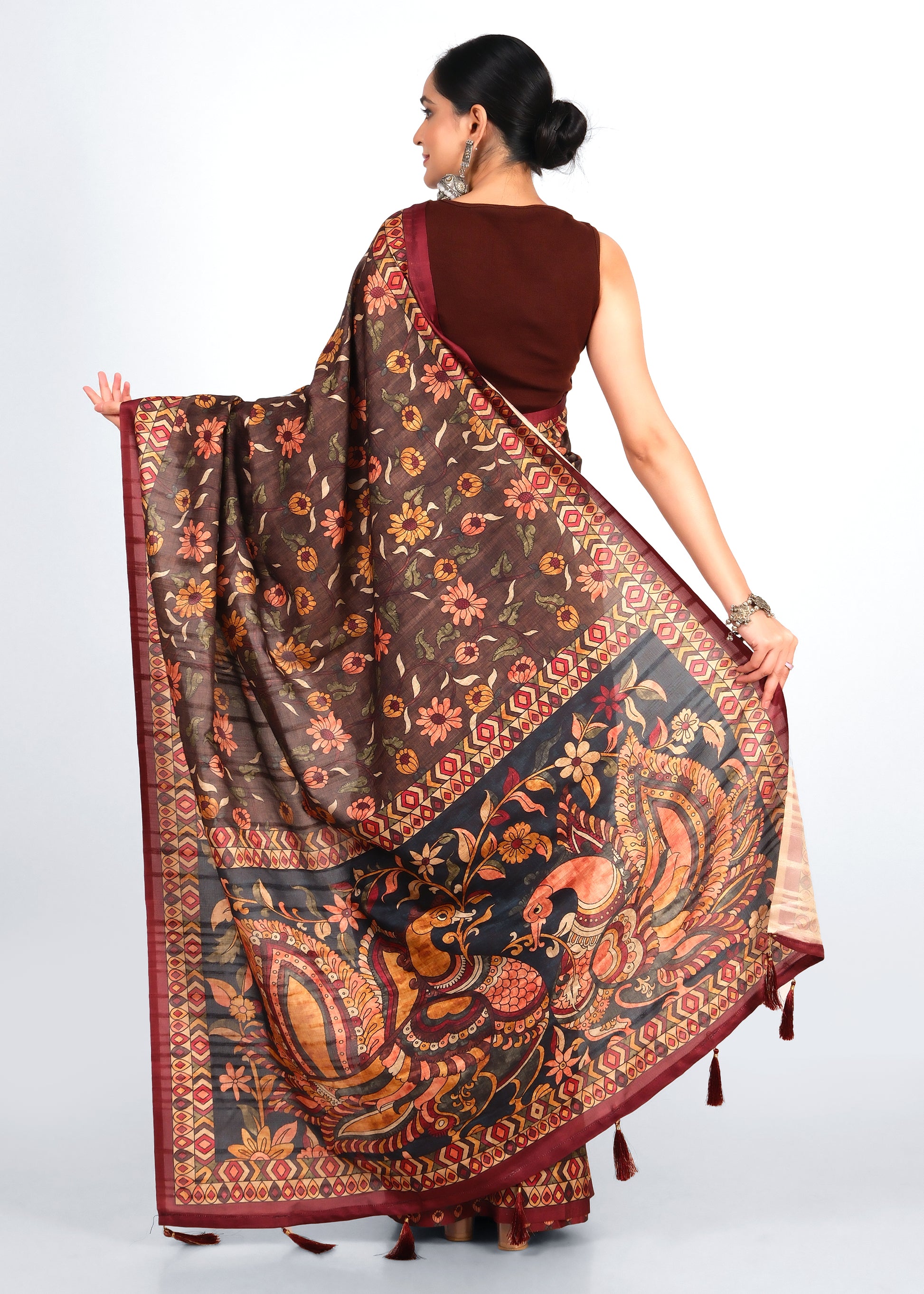 Model showcasing the back view of a brown saree with floral motifs and intricate peacock designs on the pallu, ideal for festive wear.