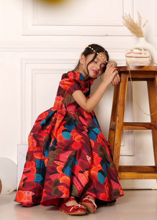 A young girl dressed in a vibrant, multicolored gown with a bold print, resting her head on a wooden stool, creating a dreamy, serene look