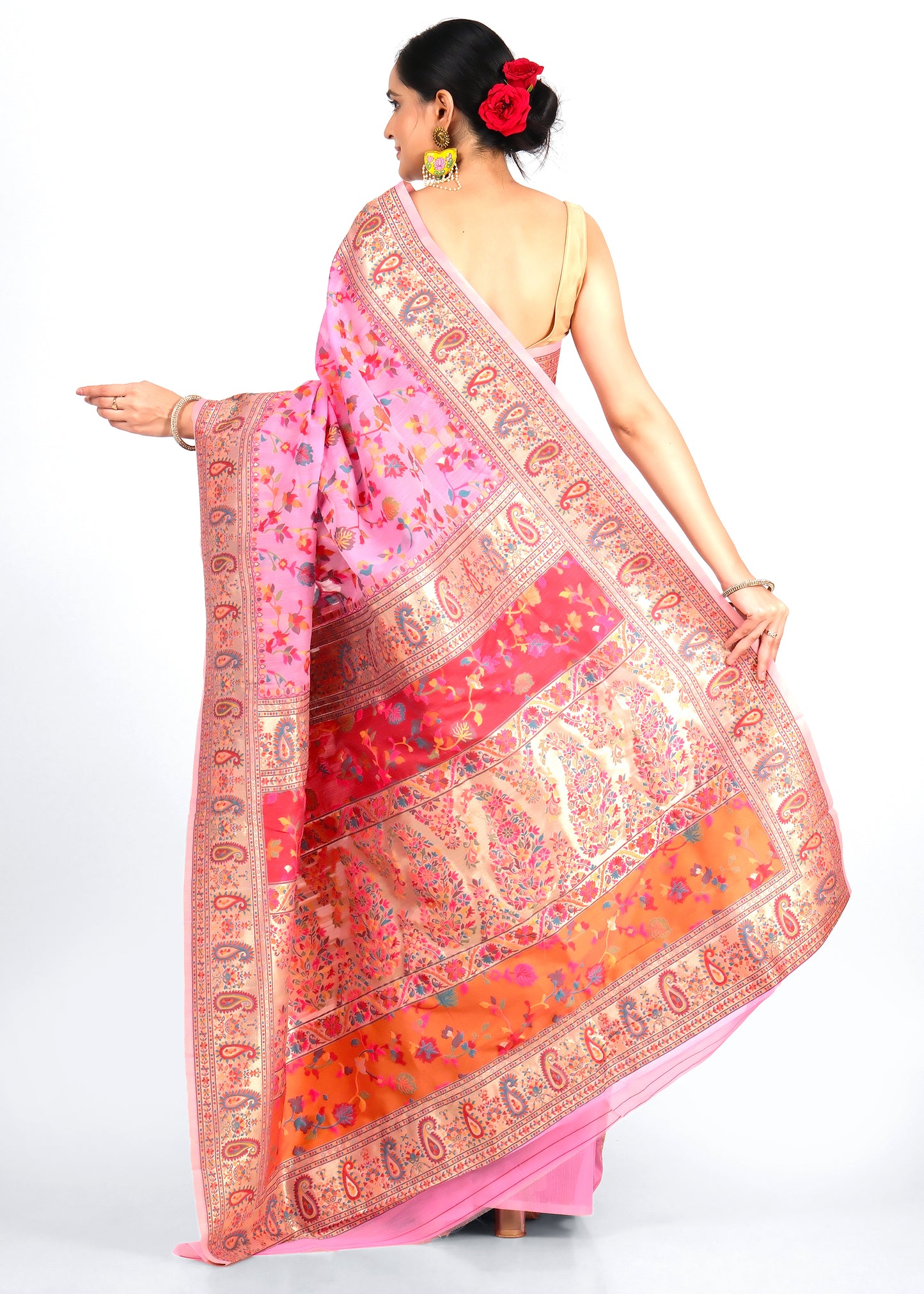 Rear view of a woman draped in a pink floral saree with golden paisley motifs, showcasing the pallu design