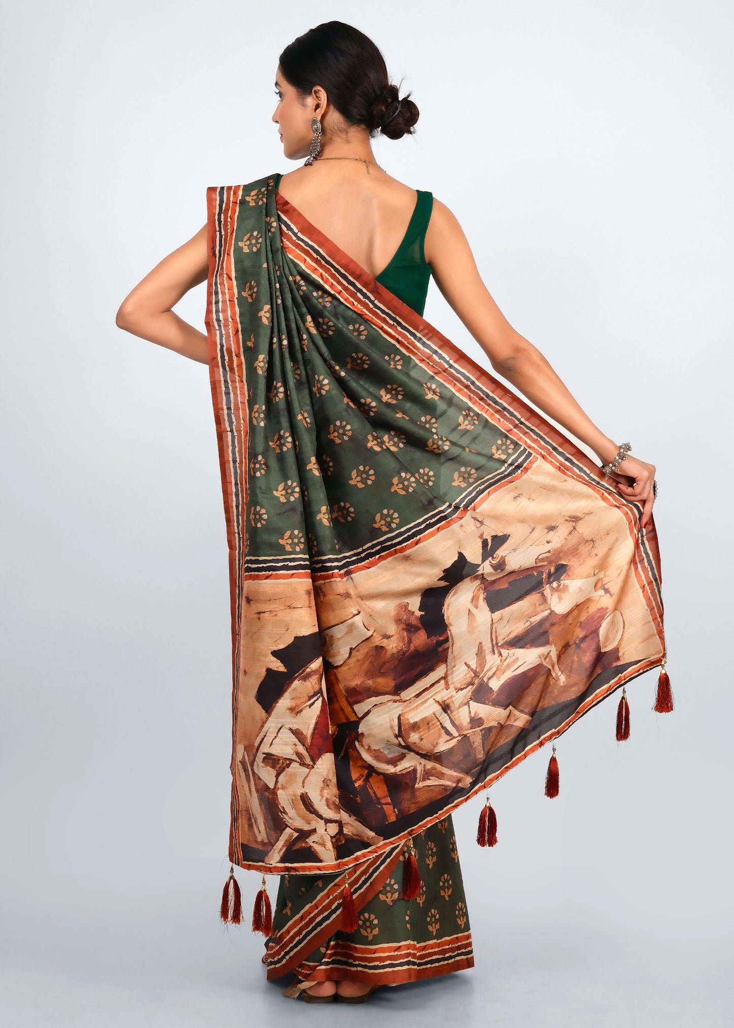 Back view of model showcasing a green saree with a unique artwork on the pallu, accented with tassels