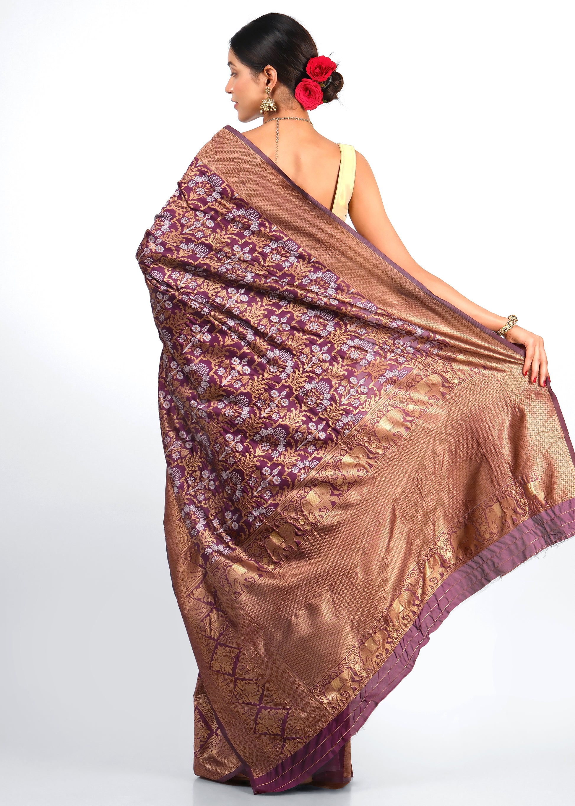 Back view of a woman draped in a rich maroon and gold silk saree adorned with delicate flower motifs and elephant designs along the border, showcasing the full drape