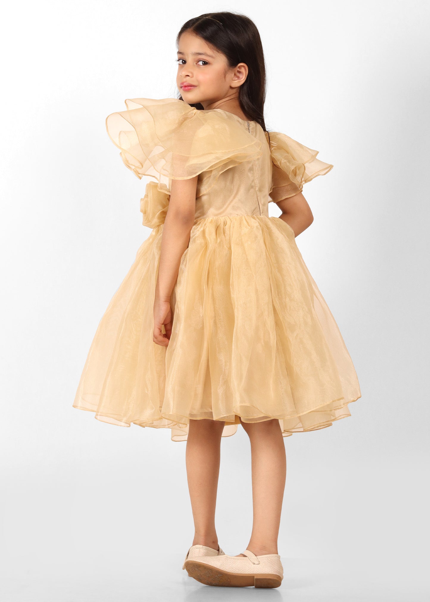  "Back view of a girl in a gold puff-sleeve dress, showing the subtle detailing of the flowy fabric and beautiful design."