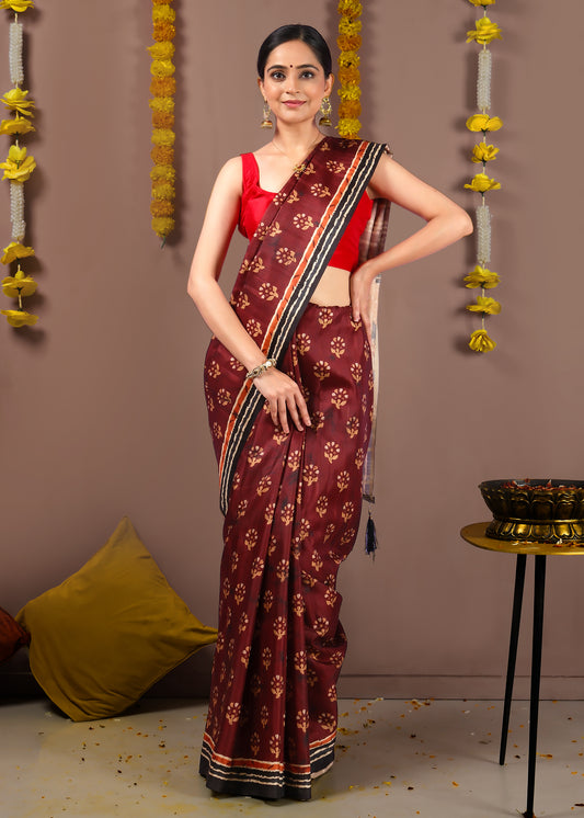 Woman wearing a classic maroon saree with intricate border detailing and red blouse for formal events