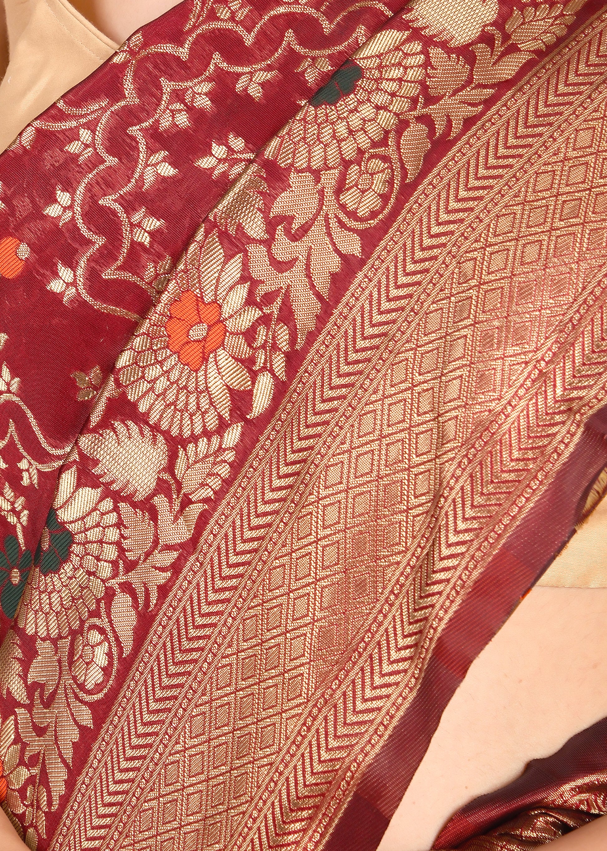 Close-up of the intricate floral and paisley patterns on a traditional red Banarasi saree with fine golden zari work