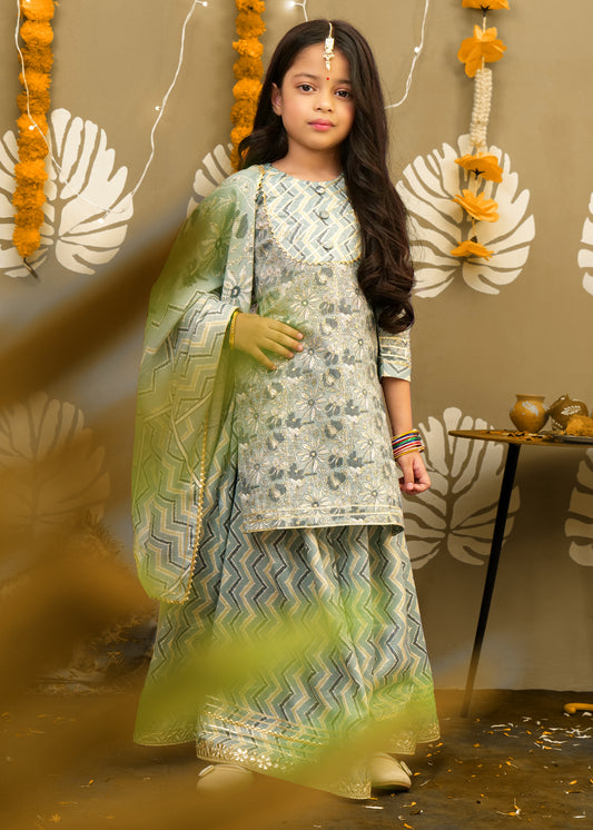 "Side view of a girl in pastel green ethnic attire with floral embroidery, chevron print palazzo, and traditional accessories."