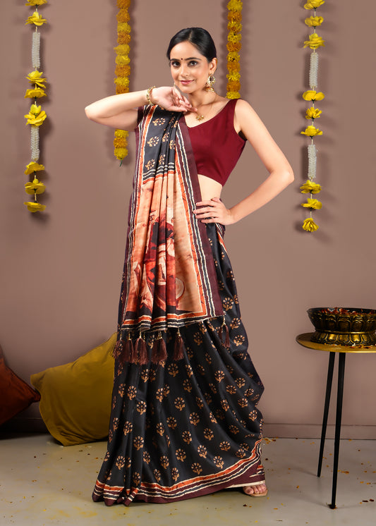 Full view of a woman gracefully showcasing a black printed saree with a colorful pallu and tassel detailing, perfect for festive occasions