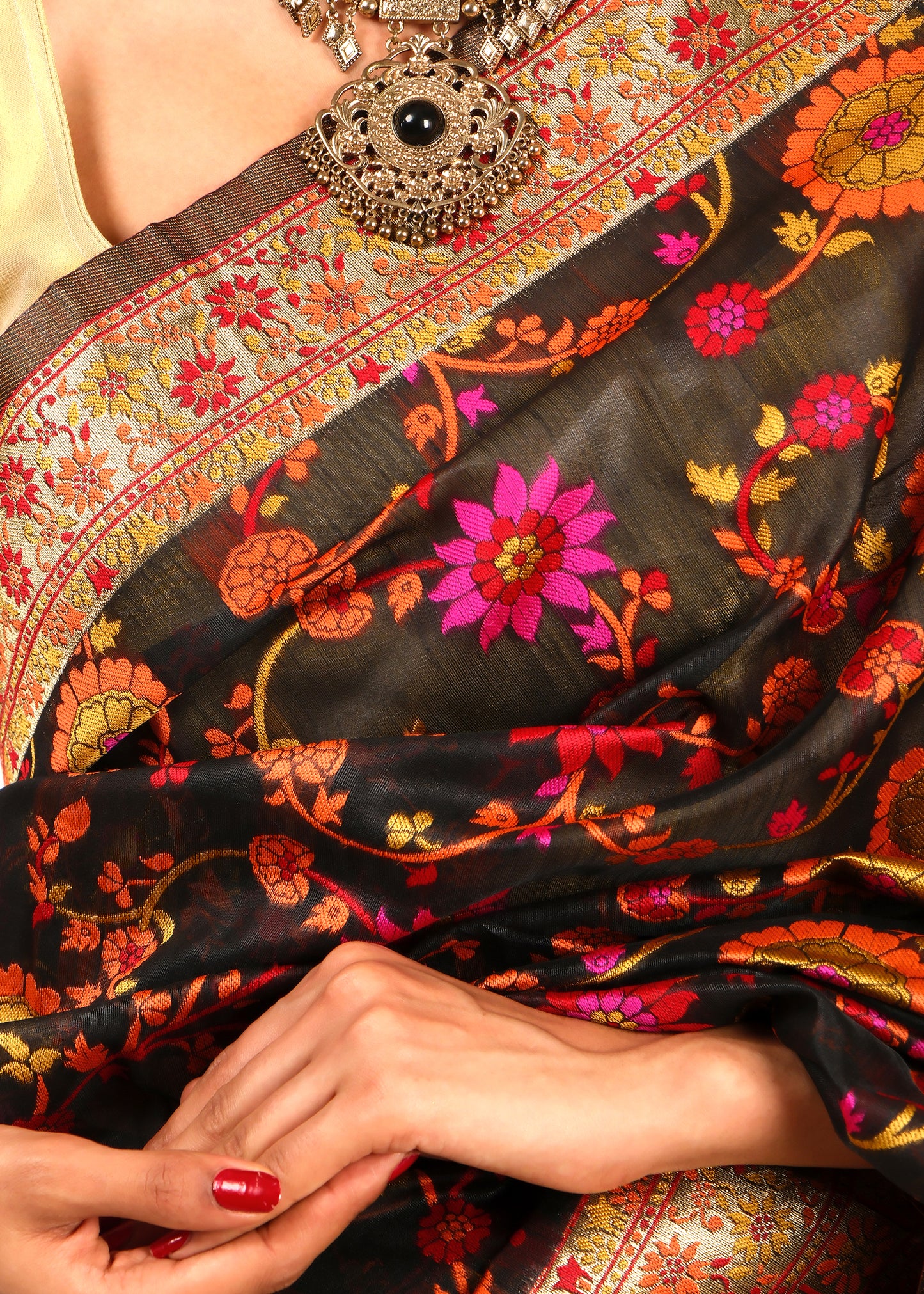 Close-up of black Banarasi silk saree with pink and orange floral embroidery and gold zari details for an opulent look