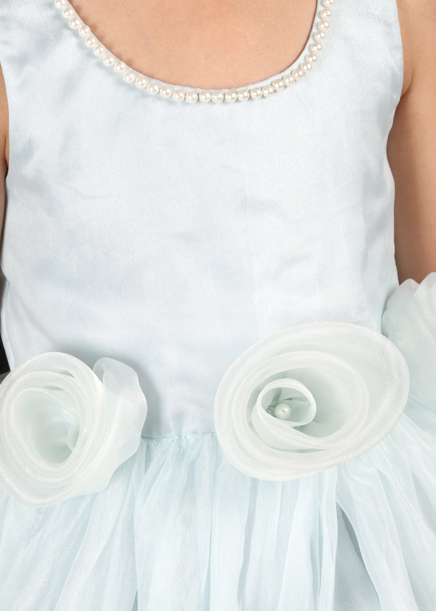 Detailed view of a pastel blue floral dress, emphasizing the soft fabric roses and pearl embellishments on the neckline.