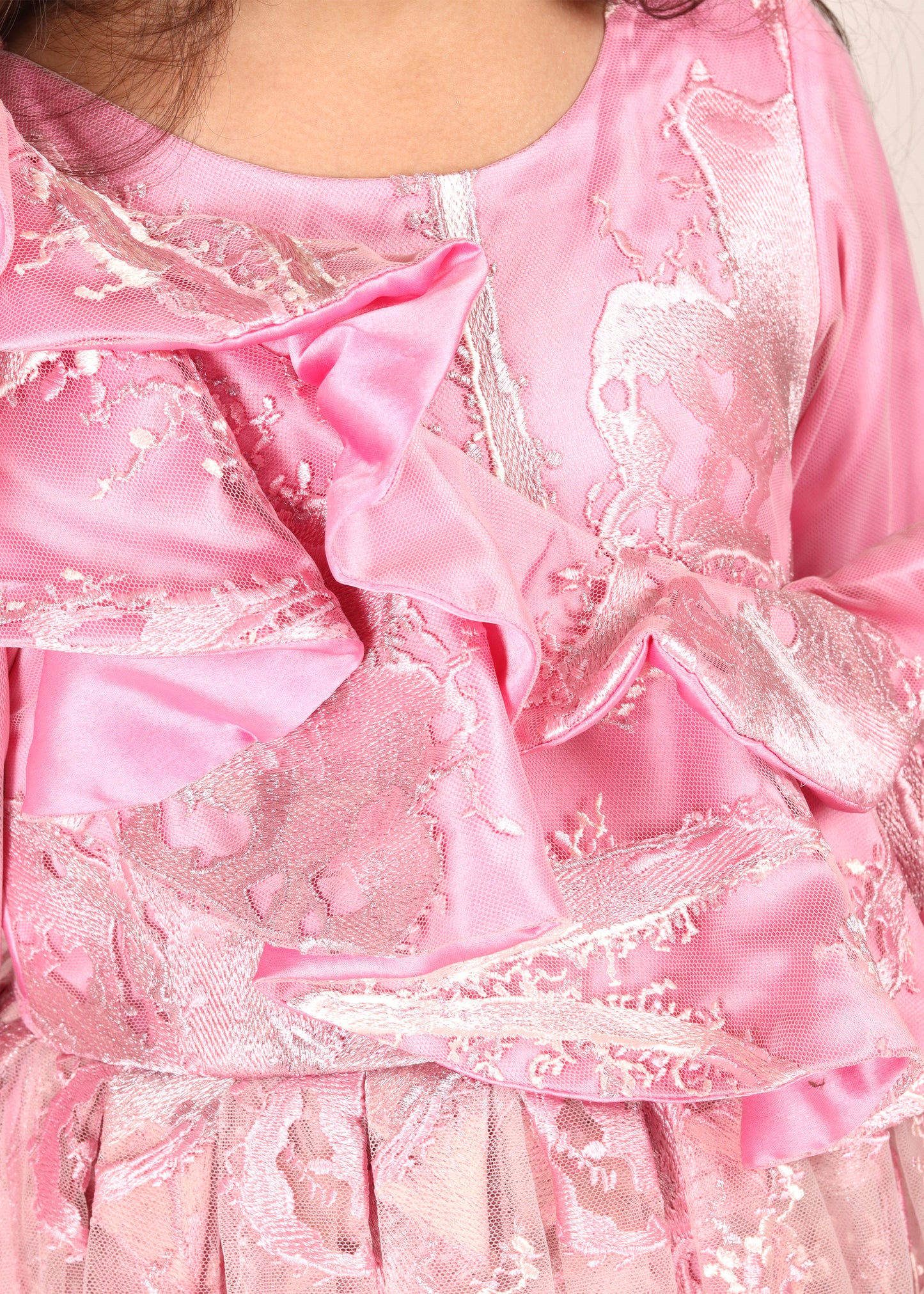 Close-up view of the intricate lace details and ruffles on a pink girls’ party gown, highlighting the luxurious fabric.