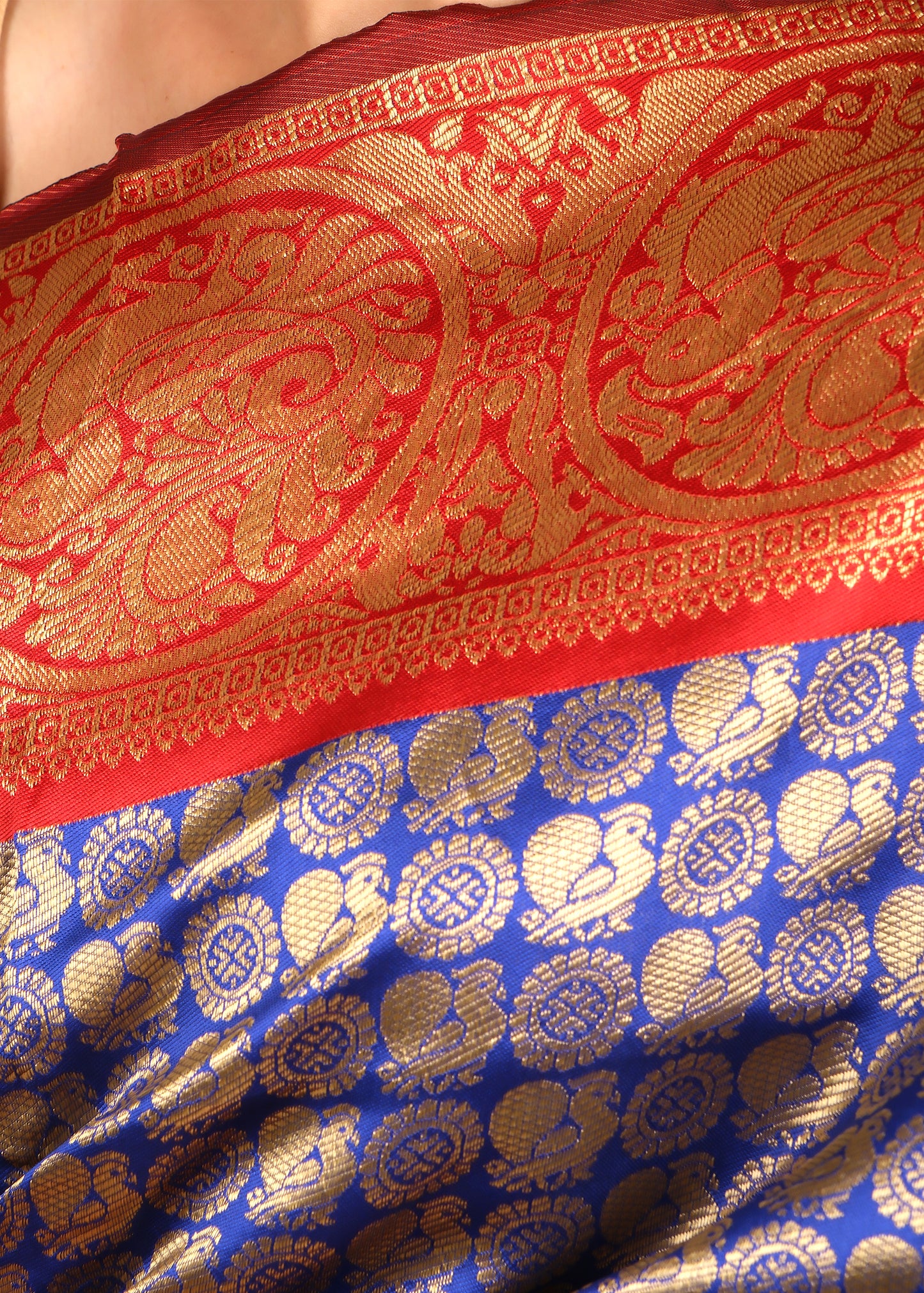 Close-up of the golden zari work on a blue Banarasi silk saree, highlighting the detailed peacock and floral motifs