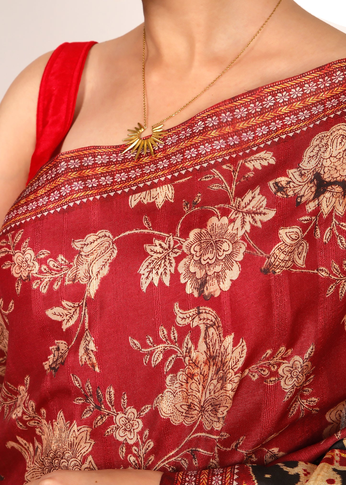 Close-up view of the floral embroidery on a red saree, highlighting the intricate details and fabric texture.