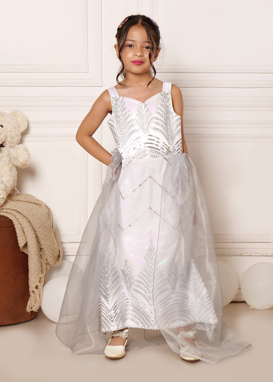 Cute girl standing in a silver gown with butterfly hair accessories, perfect for formal events and children's fashion trends