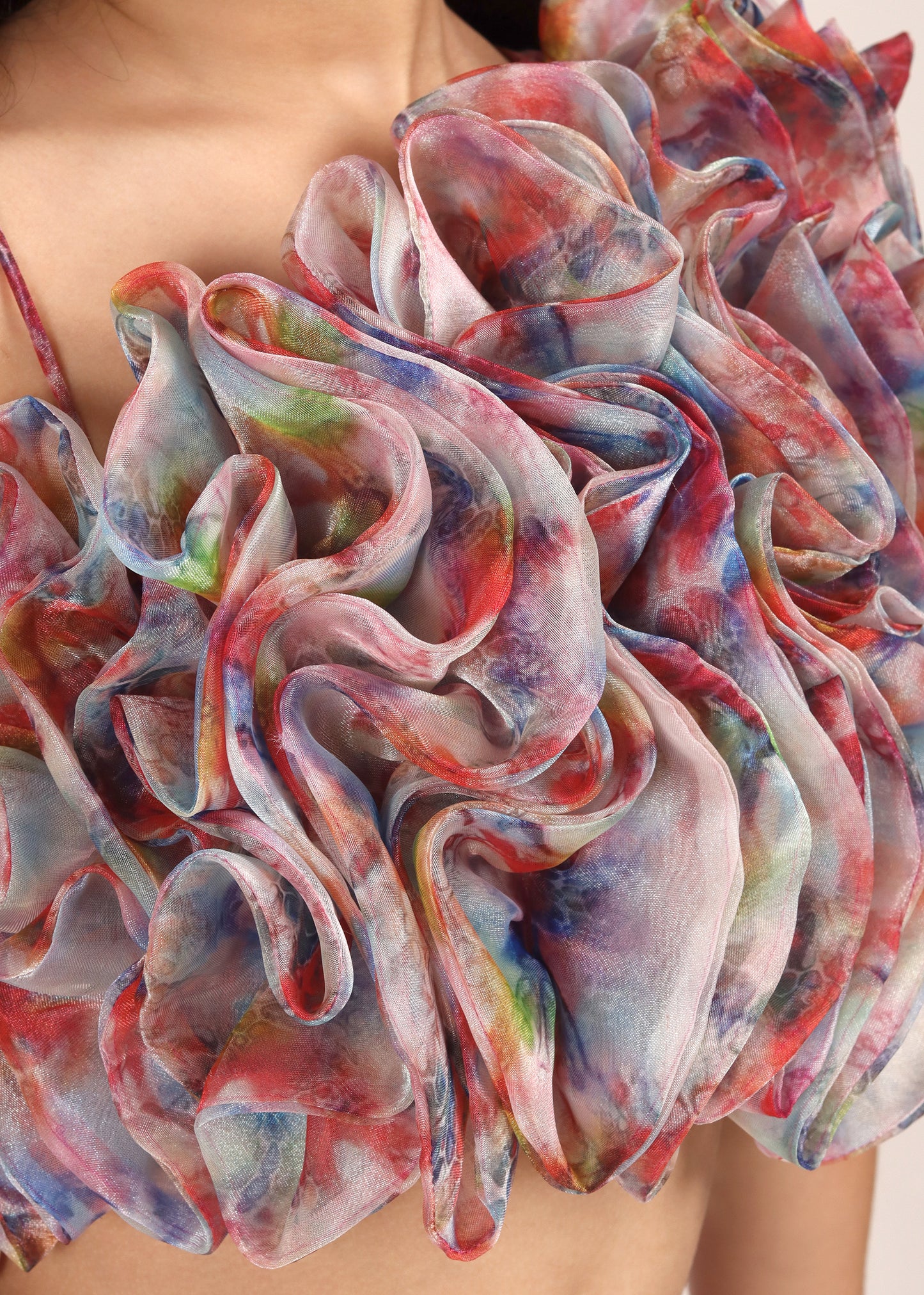 Close-up of a vibrant ruffle blouse with multi-colored floral fabric, highlighting the intricate layers and texture.