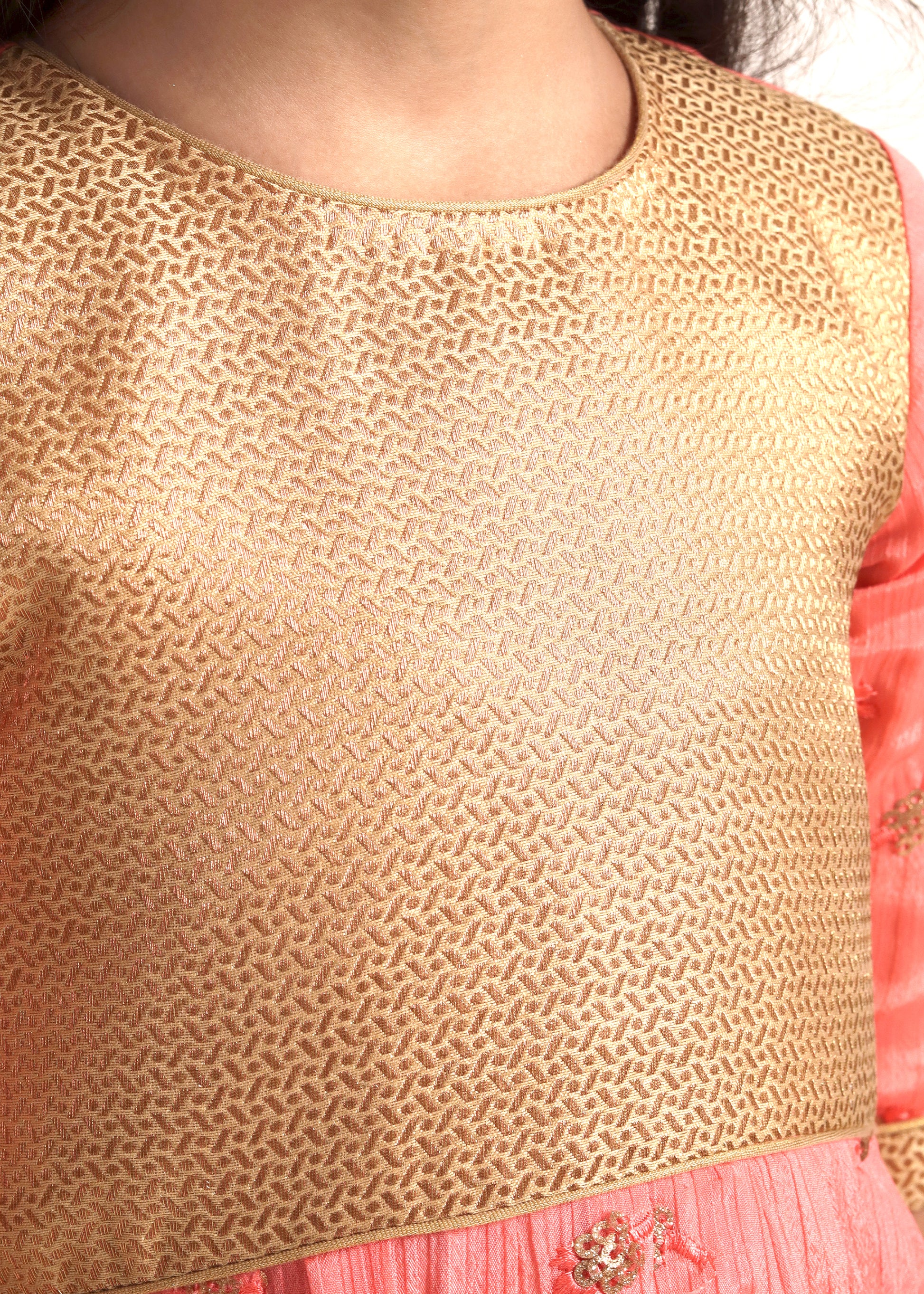 Close-up of a peach and gold embroidered dress, highlighting the detailed floral patterns and traditional craftsmanship.