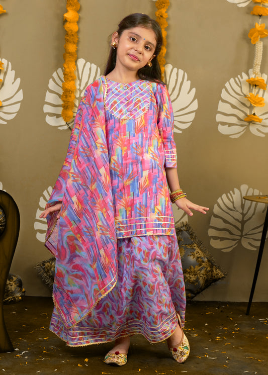 A young girl twirling in a pink and blue ethnic outfit, detailed with traditional prints and golden accents, giving a playful and joyful look for festive occasions.