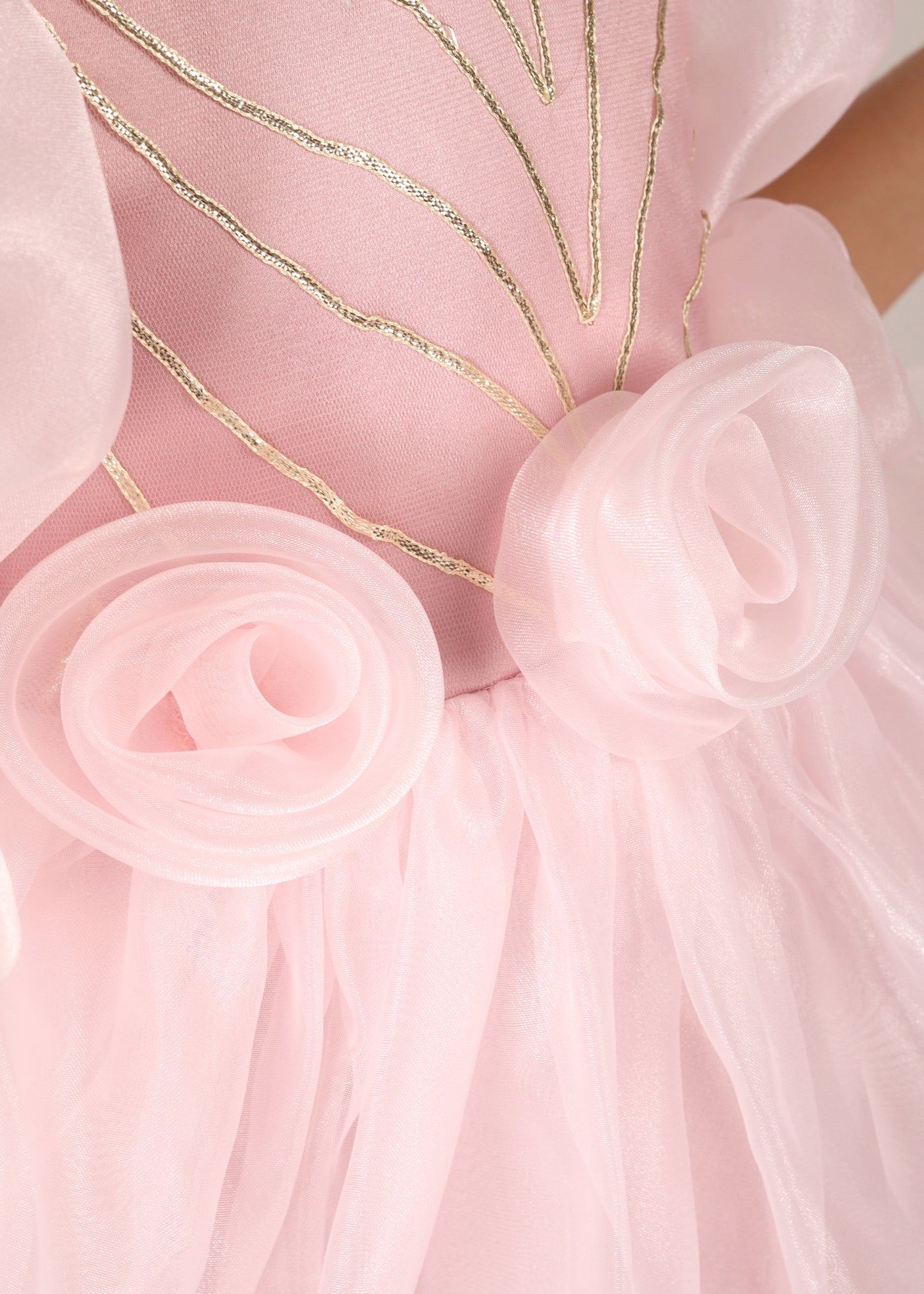 "Detailed close-up of floral accents on a pink organza dress, featuring delicate stitching and intricate design, highlighting the craftsmanship."