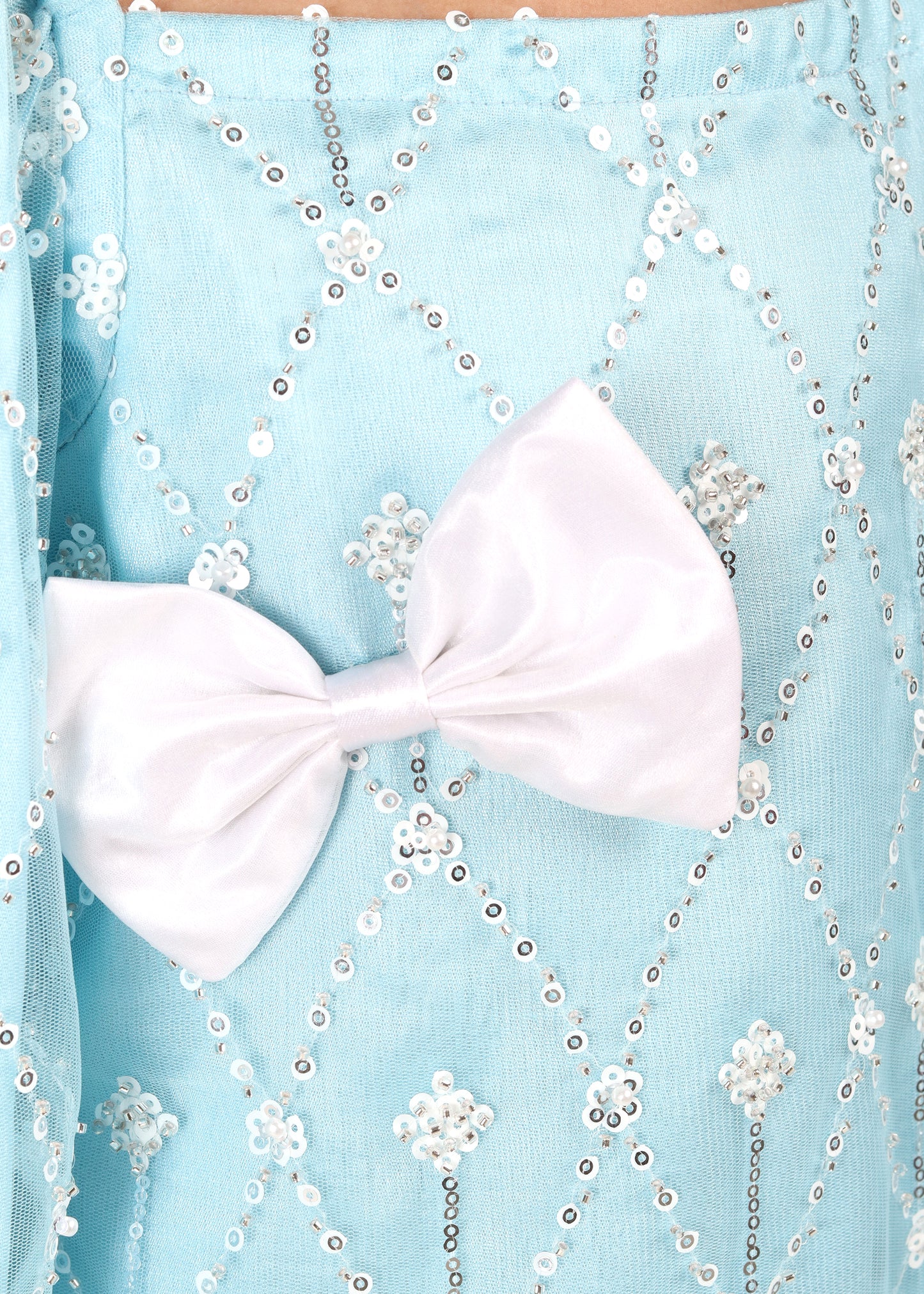 Close-up shot of a light blue dress with intricate pearl embroidery and a white satin bow, emphasizing the delicate craftsmanship and elegant design perfect for special occasions