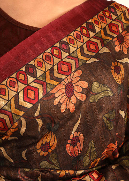 Close-up of a brown floral saree's pallu, highlighting the geometric red border and detailed floral embroidery.