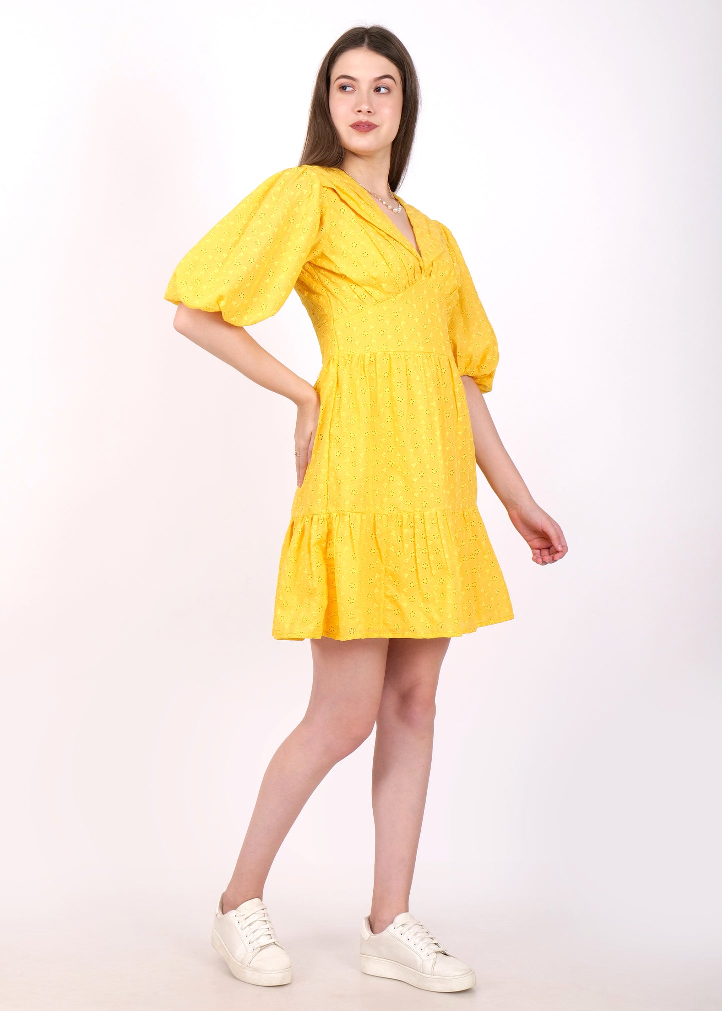 Woman in a stylish yellow puff-sleeved dress, showing off her chic summer style with a casual stance