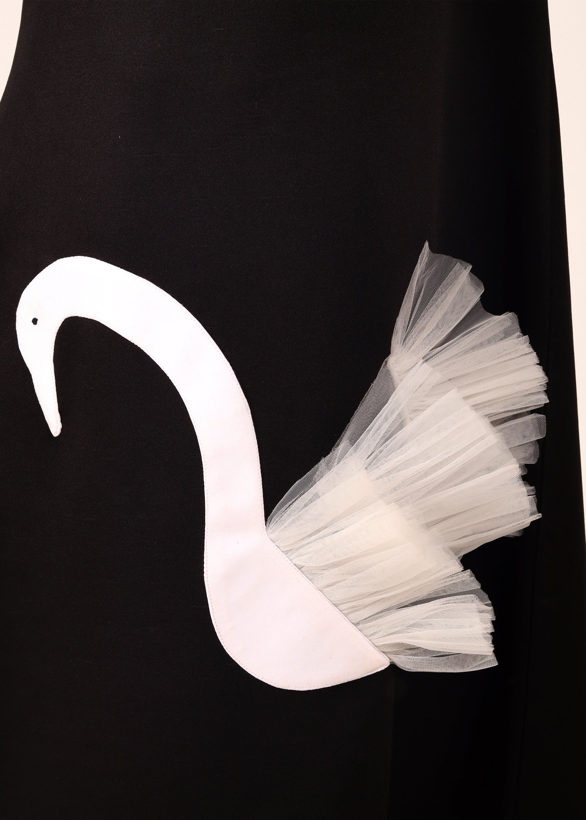 Close-up of a white swan applique with layered tulle detail on a black dress, highlighting unique design elements in children's fashion