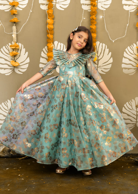 Girl twirling in a full-length teal and gold floral gown, showing off the elegant flow and shimmer of the fabric.