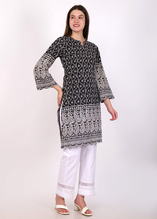 Model in a black ethnic kurta with white embroidery, posing side view with minimalistic style and white pants