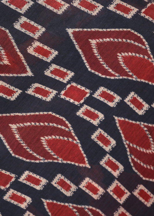  Close-up of the red and black saree's intricate geometric pattern, highlighting the detailed craftsmanship on the fabric.